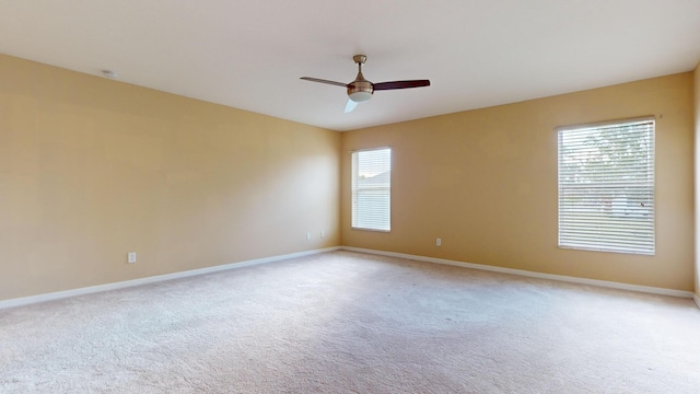 unfurnished room featuring light carpet, baseboards, and a ceiling fan