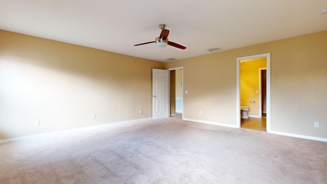 spare room with light carpet, ceiling fan, visible vents, and baseboards