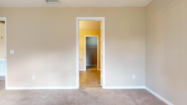 spare room with visible vents, baseboards, and light colored carpet