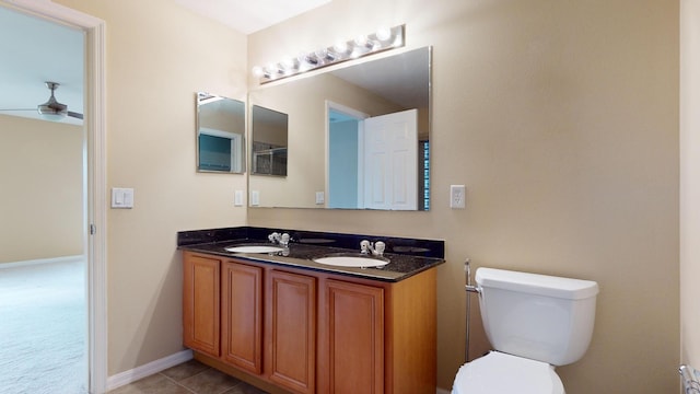 bathroom with toilet, ceiling fan, double vanity, and a sink