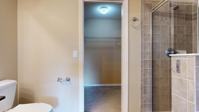 full bath featuring a stall shower, a walk in closet, and toilet