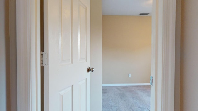 hall featuring light carpet, visible vents, and baseboards