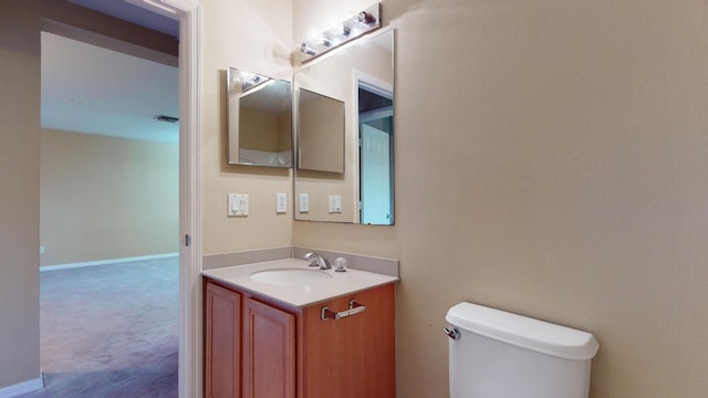 half bath with toilet, visible vents, baseboards, and vanity