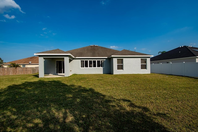 back of property featuring a fenced backyard, a lawn, and stucco siding