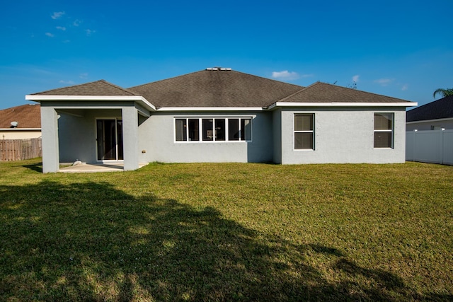 rear view of house featuring a lawn, a patio area, fence, and stucco siding