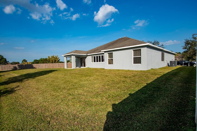 back of property featuring stucco siding, fence, and a lawn