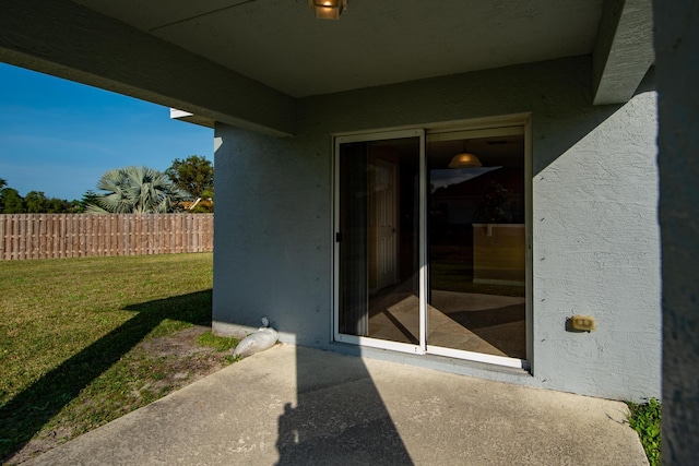 view of exterior entry with a lawn and a patio