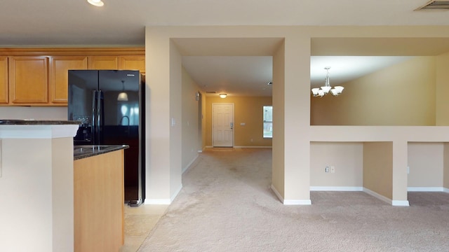 kitchen with an inviting chandelier, light colored carpet, and black fridge with ice dispenser