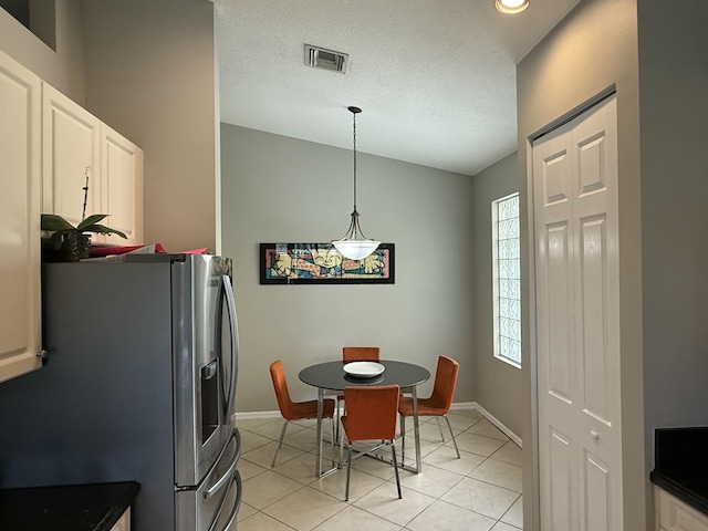 tiled dining space featuring lofted ceiling and a textured ceiling