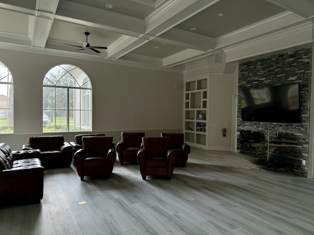 living room with ceiling fan, coffered ceiling, ornamental molding, light hardwood / wood-style floors, and beamed ceiling