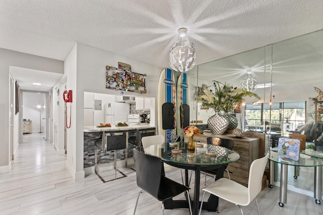 dining area featuring an inviting chandelier, a textured ceiling, and light hardwood / wood-style flooring