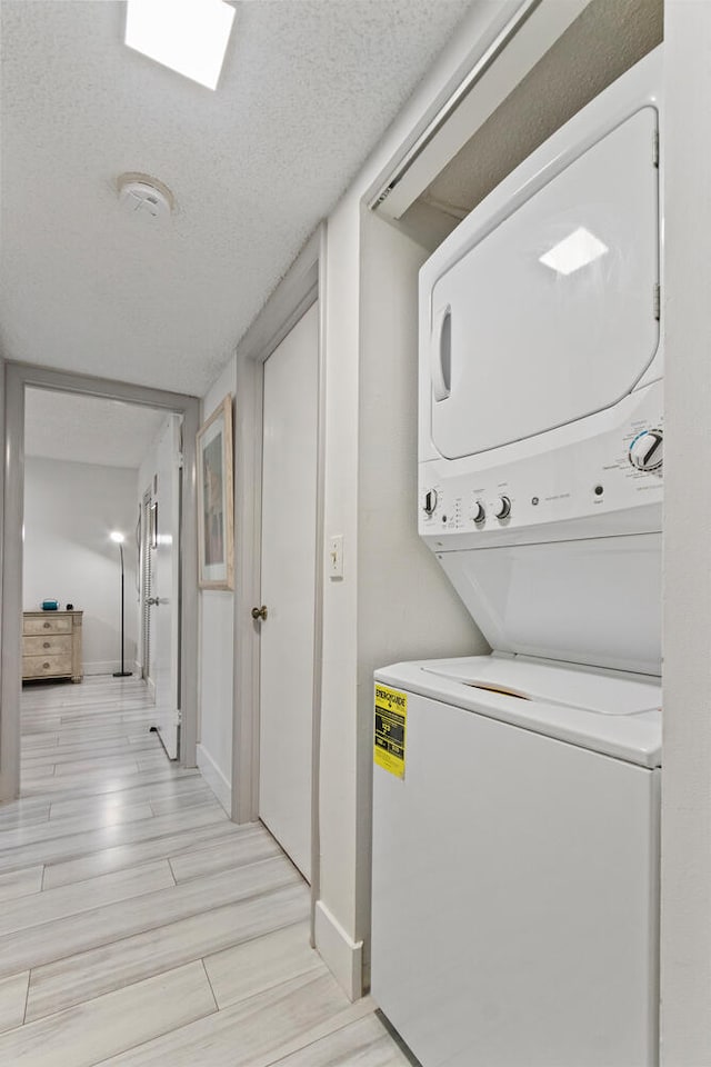 laundry room with stacked washer and clothes dryer and a textured ceiling