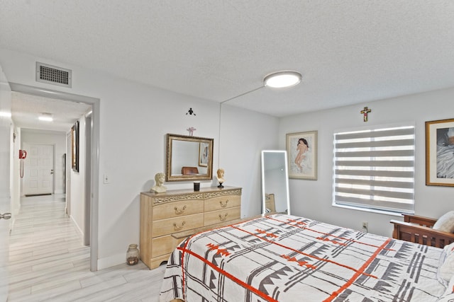 bedroom with a textured ceiling and light wood-type flooring