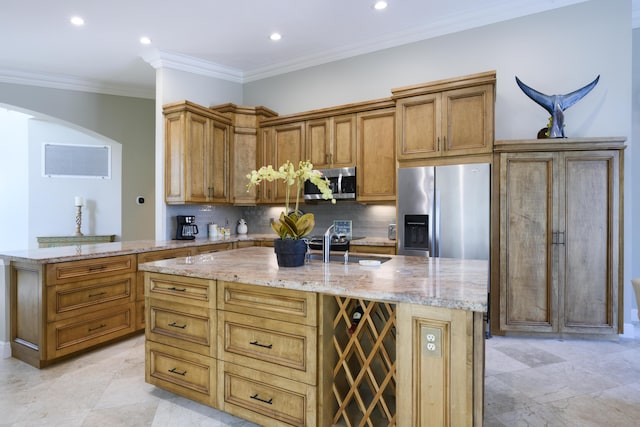 kitchen featuring light stone counters, appliances with stainless steel finishes, a kitchen island with sink, and decorative backsplash