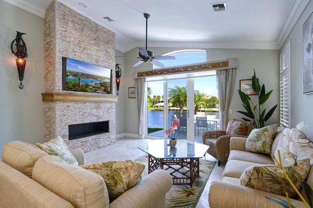 living room with ornamental molding, a stone fireplace, and ceiling fan