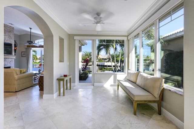 sunroom with a stone fireplace and ceiling fan