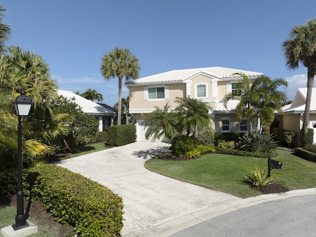 view of front facade featuring concrete driveway, a tiled roof, an attached garage, a front lawn, and stucco siding