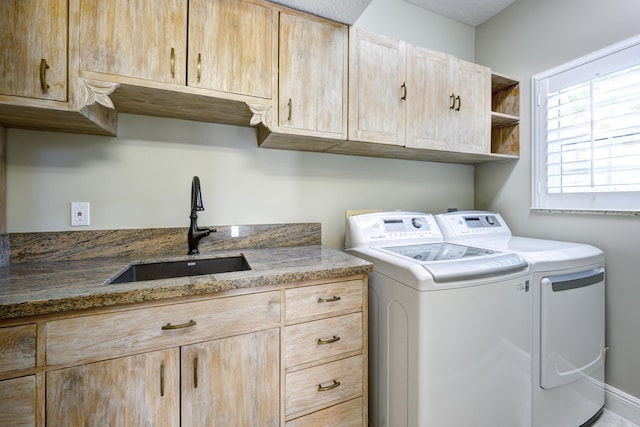 clothes washing area featuring washer and dryer, sink, and cabinets