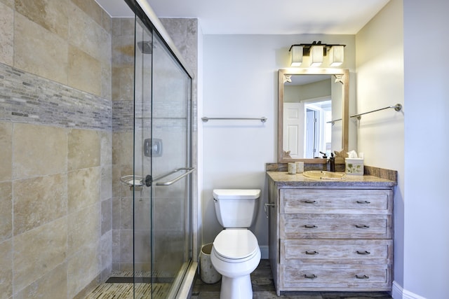 bathroom featuring vanity, toilet, and a shower with shower door