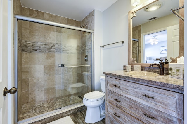 bathroom with a shower with door, vanity, and toilet