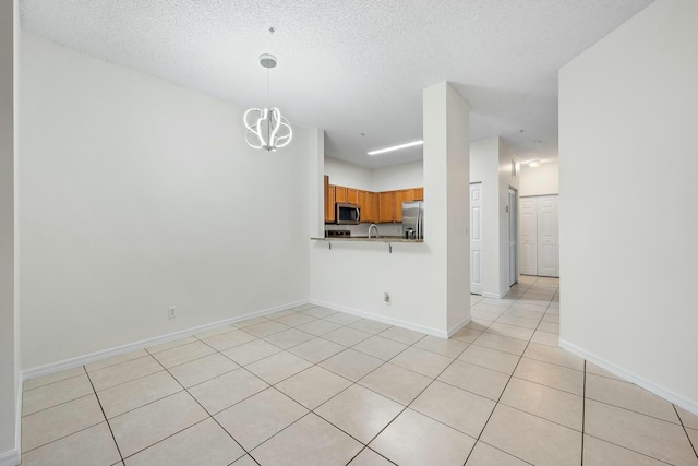 kitchen with hanging light fixtures, a textured ceiling, a chandelier, and appliances with stainless steel finishes