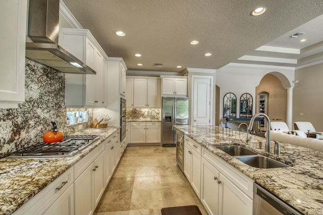 kitchen featuring appliances with stainless steel finishes, sink, white cabinets, and wall chimney exhaust hood