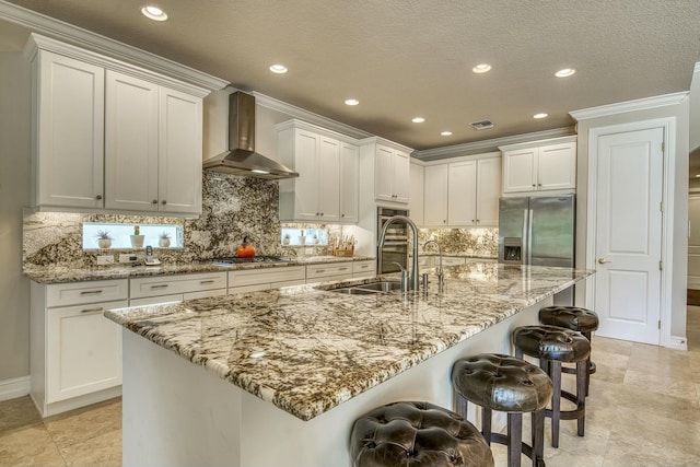 kitchen featuring a breakfast bar, sink, stainless steel appliances, a large island, and wall chimney range hood