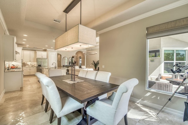 dining area with ornamental molding, a chandelier, and sink