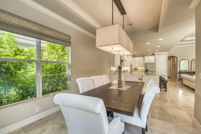 dining space with a tray ceiling, crown molding, and a wealth of natural light