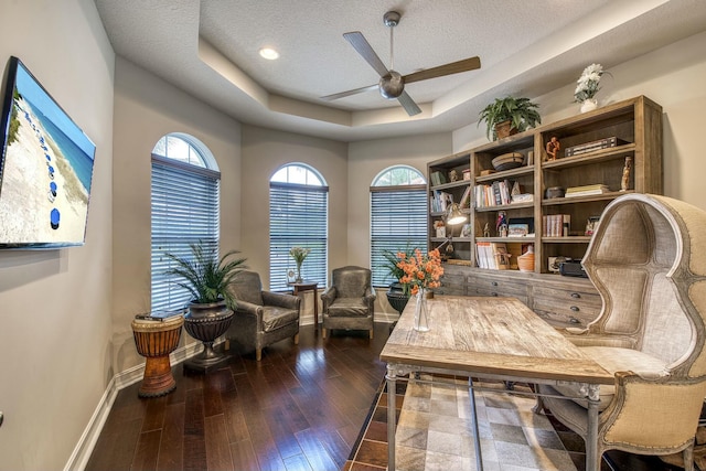 office area featuring a raised ceiling, dark hardwood / wood-style floors, a textured ceiling, and ceiling fan