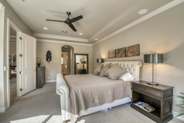 carpeted bedroom with ceiling fan, a tray ceiling, ornamental molding, and a textured ceiling