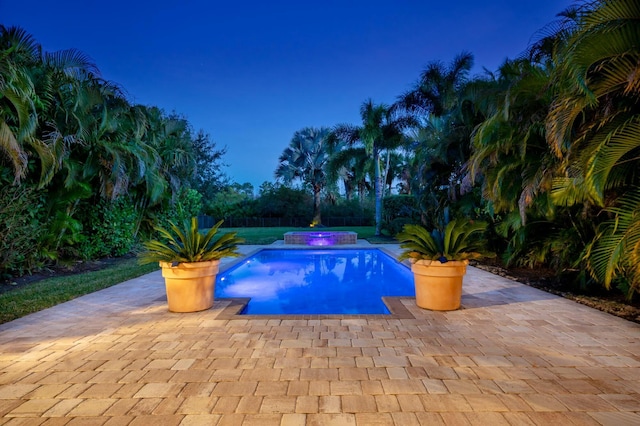 pool at dusk featuring a patio