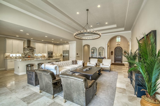 living room with ornamental molding, a raised ceiling, and sink