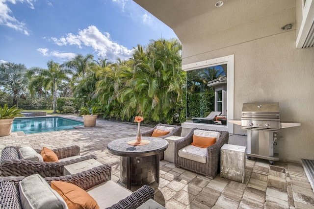 view of patio with a swimming pool with hot tub, area for grilling, and an outdoor fire pit