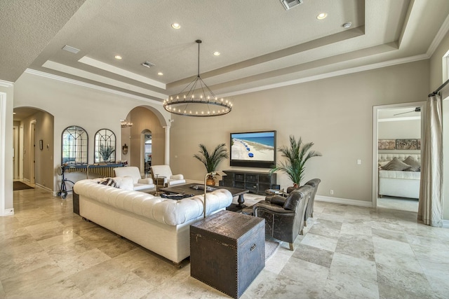 living room featuring a tray ceiling, ornamental molding, a chandelier, and a textured ceiling