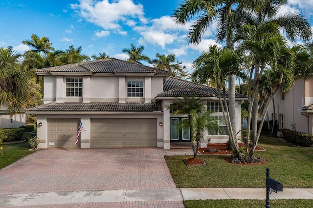 view of front of property featuring a garage, a tiled roof, decorative driveway, stucco siding, and a front lawn