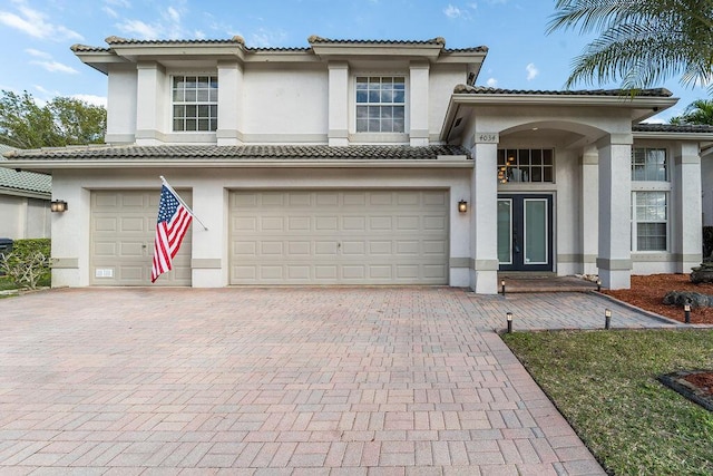 view of front of house with stucco siding, french doors, decorative driveway, and a garage