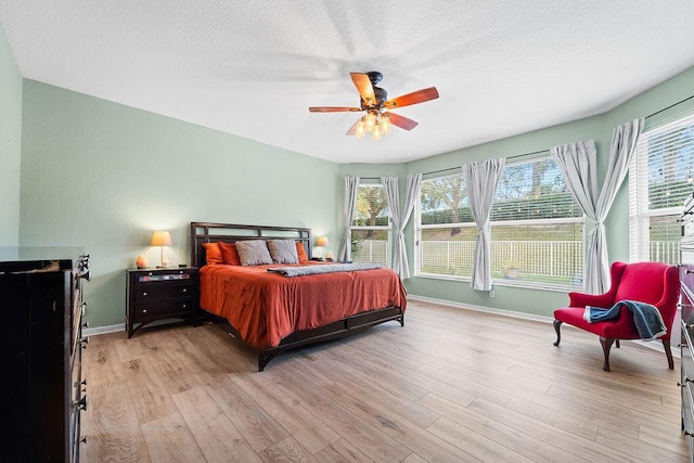 bedroom with multiple windows, ceiling fan, and light hardwood / wood-style floors