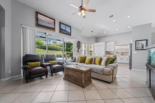 living room with light tile patterned floors, baseboards, a high ceiling, and ceiling fan