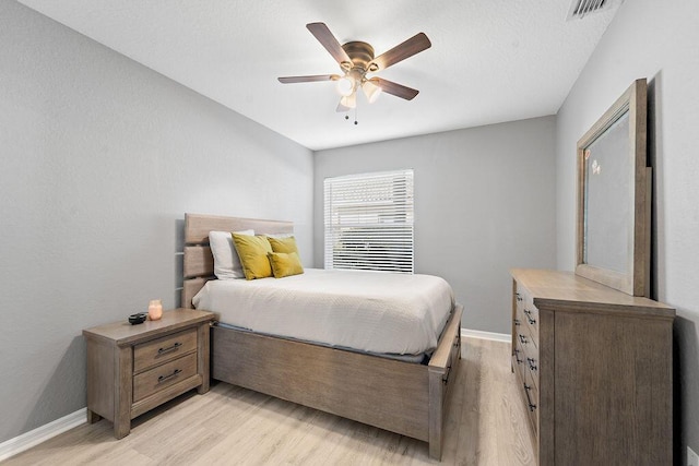 bedroom with visible vents, baseboards, light wood-style floors, and a ceiling fan