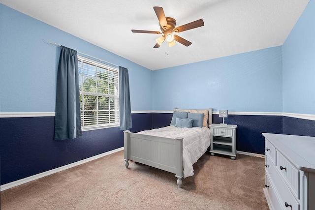 carpeted bedroom with a ceiling fan, baseboards, and a textured wall