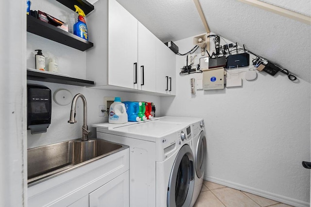 clothes washing area with washer and clothes dryer, a sink, cabinet space, light tile patterned floors, and baseboards