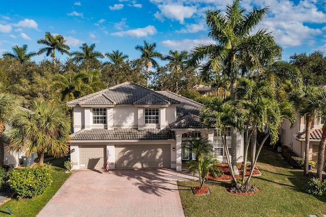 view of front of home with a front lawn, a tile roof, stucco siding, decorative driveway, and an attached garage