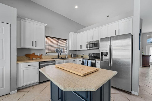 kitchen featuring stainless steel appliances, a center island, white cabinets, and a sink