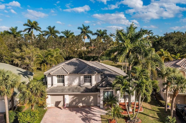 view of front of home with a tiled roof, a front yard, stucco siding, decorative driveway, and an attached garage