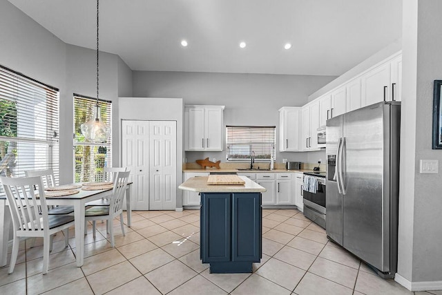 kitchen featuring a kitchen island, light countertops, white cabinets, stainless steel appliances, and a sink