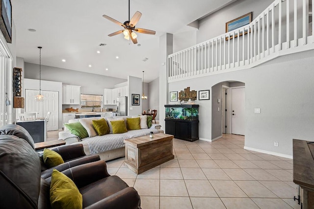 tiled living room featuring a towering ceiling, sink, and ceiling fan