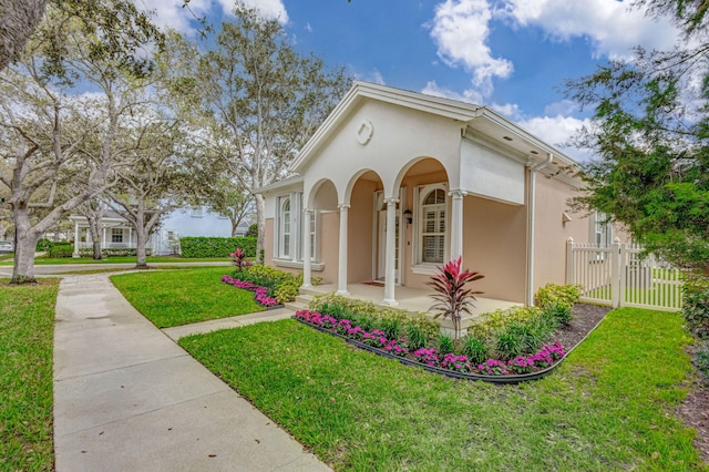 mediterranean / spanish home with a front yard, stucco siding, and a gate