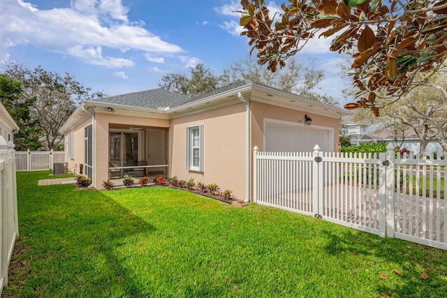 view of side of property with a yard, stucco siding, a garage, and a sunroom