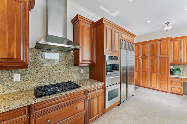 kitchen with light stone counters, appliances with stainless steel finishes, and wall chimney range hood